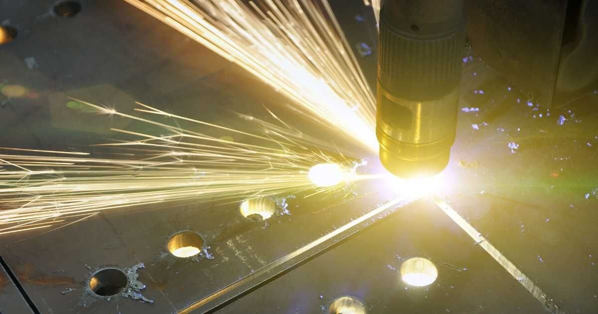 Plasma cutting machine with bright sparks cutting through a steel plate.